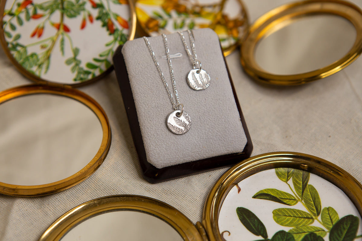 Fern leaf imprinted sterling silver round pendants on figaro chains.