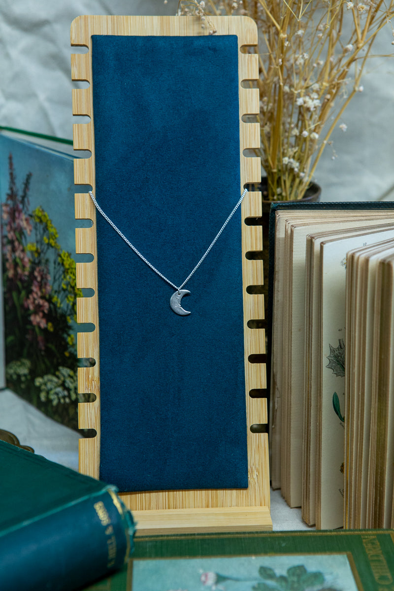 A handmade fine silver moon necklace, each hand carved with different facial expressions.